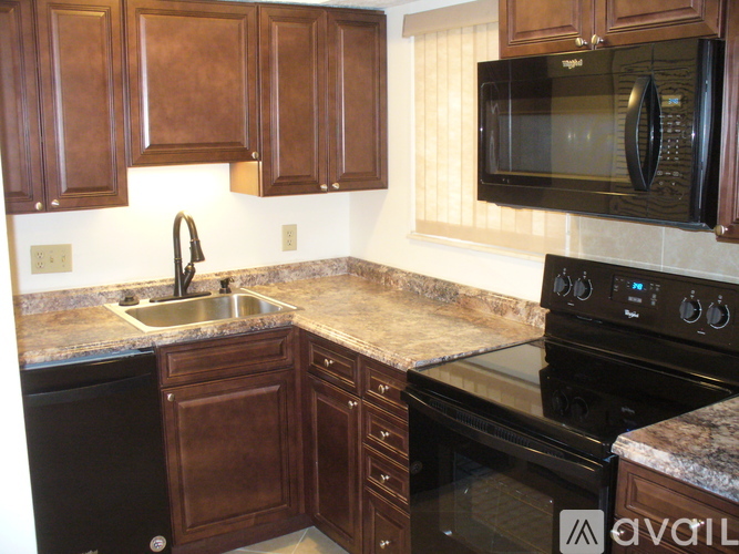 A kitchen with brown cabinets and a black stove top oven.