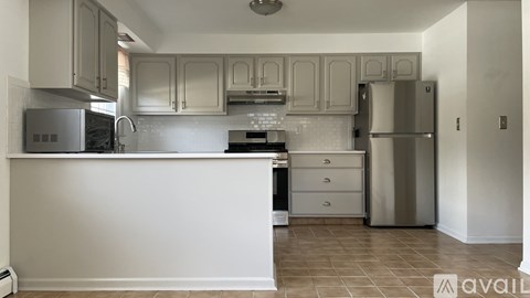 A kitchen with white cabinets and a stainless steel refrigerator.