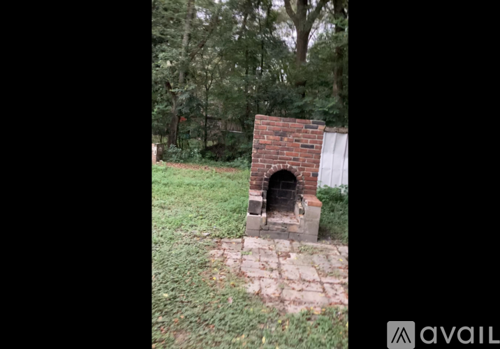 A brick oven is in the middle of a grassy area.