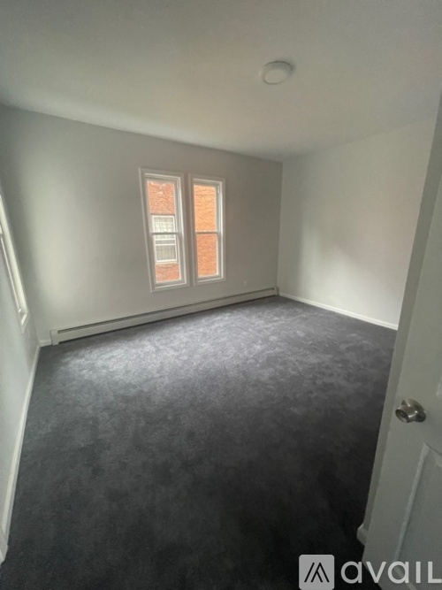 A room with a carpeted floor and a window with blinds.