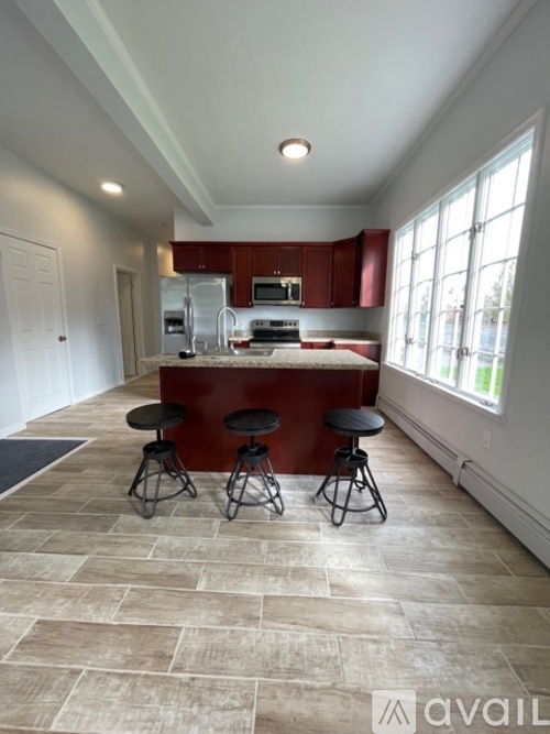 A kitchen with a red counter and bar stools.