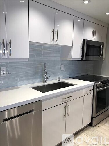 A modern kitchen with white cabinets and stainless steel appliances.
