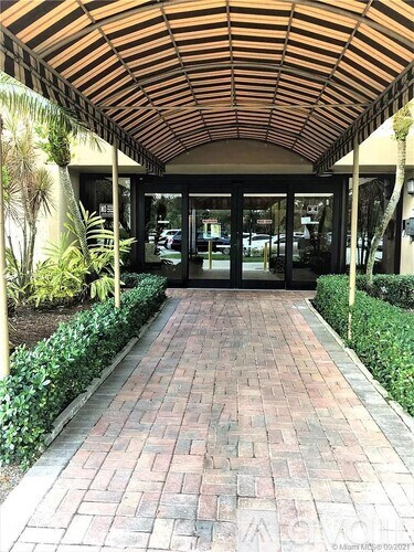 A covered walkway with brick flooring and a wooden roof.