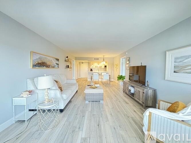 A spacious living room with a white sofa, a wooden coffee table, and a television.