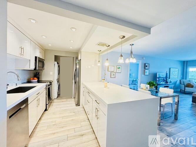A modern kitchen with a white countertop and wooden flooring.