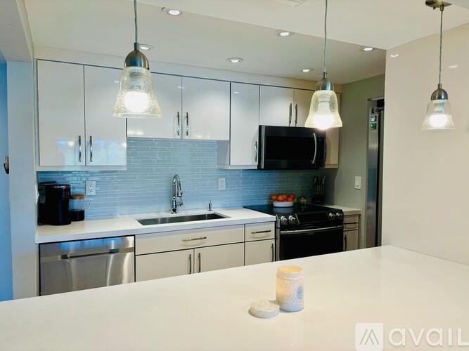 A modern kitchen with a white countertop and stainless steel appliances.