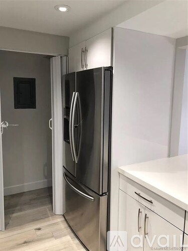 A stainless steel refrigerator is in a kitchen with white cabinets.