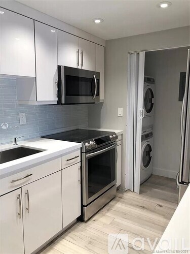 A modern kitchen with white cabinets and a black microwave.