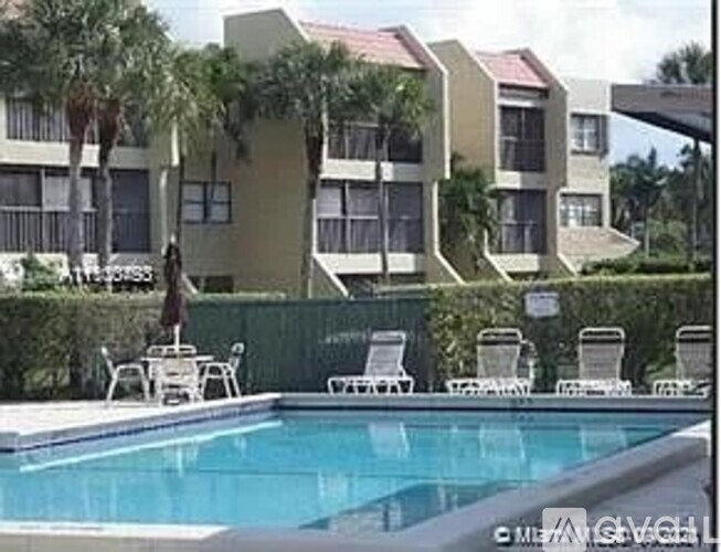 A swimming pool in front of a building with lounge chairs around it.