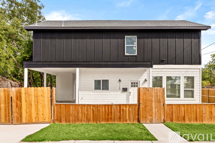 A black and white house with a wooden fence in front.