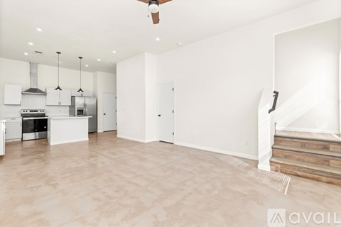 A spacious kitchen with white cabinets and a wooden staircase.