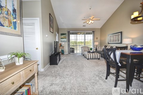 A living room with a ceiling fan and a dining table with chairs.