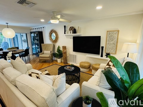 A living room with a white couch and a flat screen TV mounted on the wall.