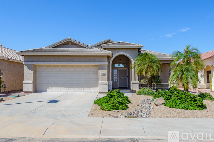 A house with a driveway and a palm tree in front.