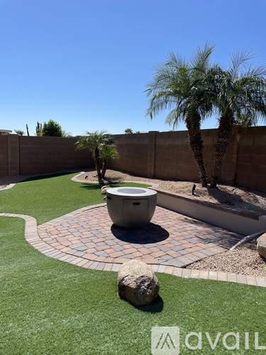 A backyard with a fountain, grass, and a wall.