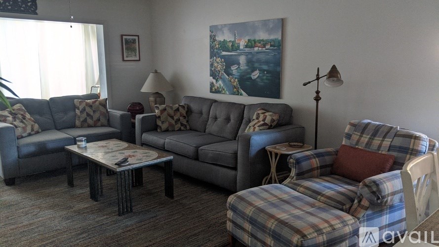 A living room with a grey couch, a coffee table, and a painting on the wall.