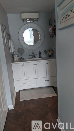 A bathroom with a round mirror and a white cabinet.
