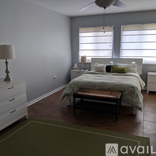 A bedroom with a bed, nightstand, and a bench.