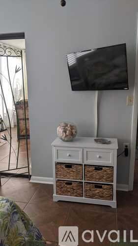 A white TV stand with baskets underneath it.
