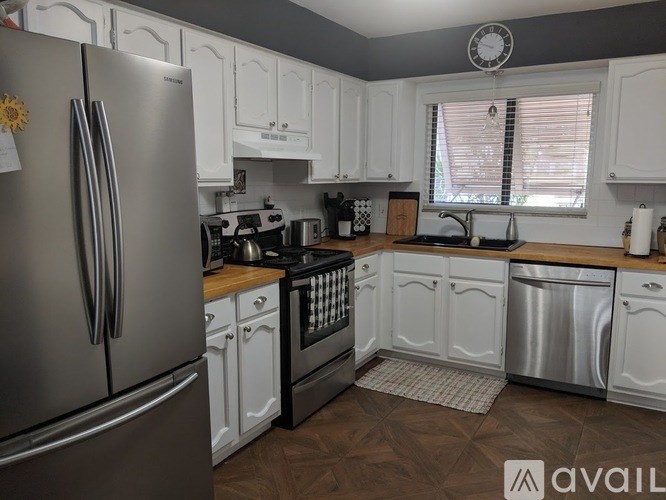 A kitchen with white cabinets and a stainless steel refrigerator.