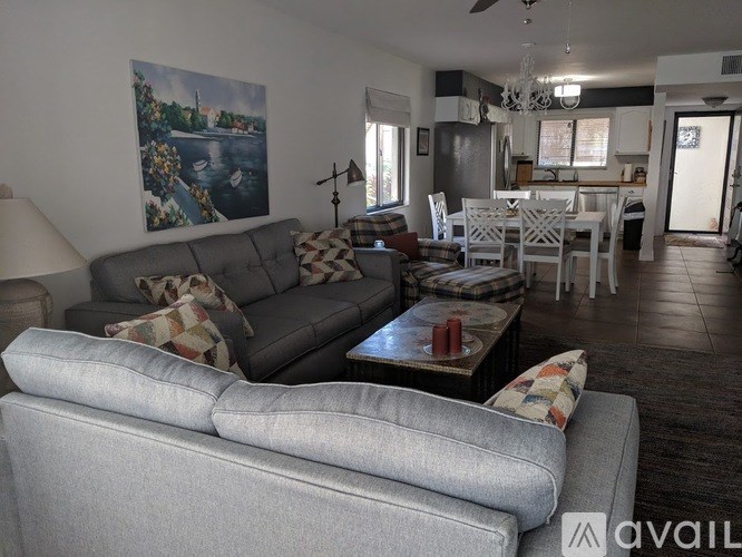 A living room with a grey couch and a painting on the wall.