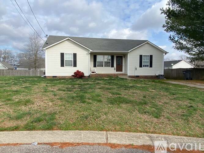 A house with a white exterior and a grey roof is surrounded by a grassy lawn.