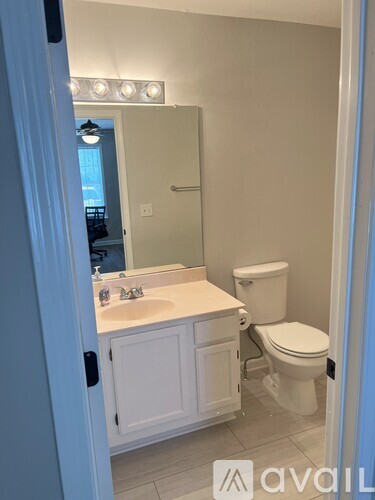 A bathroom with a toilet, sink, and mirror.