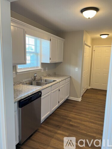 A kitchen with white cabinets and a wooden floor.