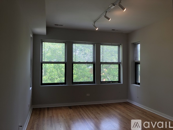 A room with wooden floors and three windows.