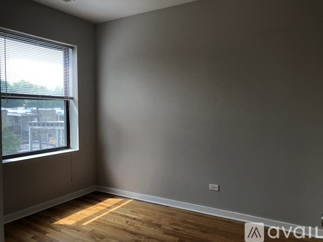 A room with wooden flooring and a window letting in sunlight.
