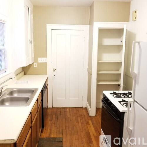 A kitchen with a white fridge, sink and cabinets.