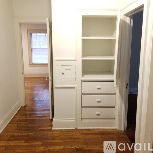 A room with a white door and a white cabinet with drawers.