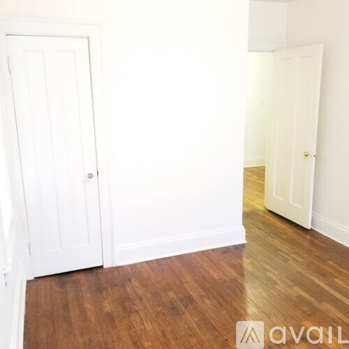 A room with a white door and wooden floor.