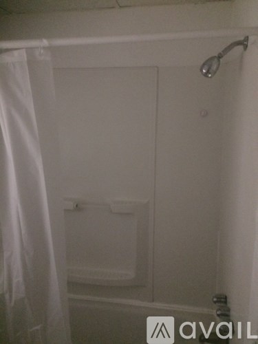 A white bathroom with a shower curtain and a shower head.