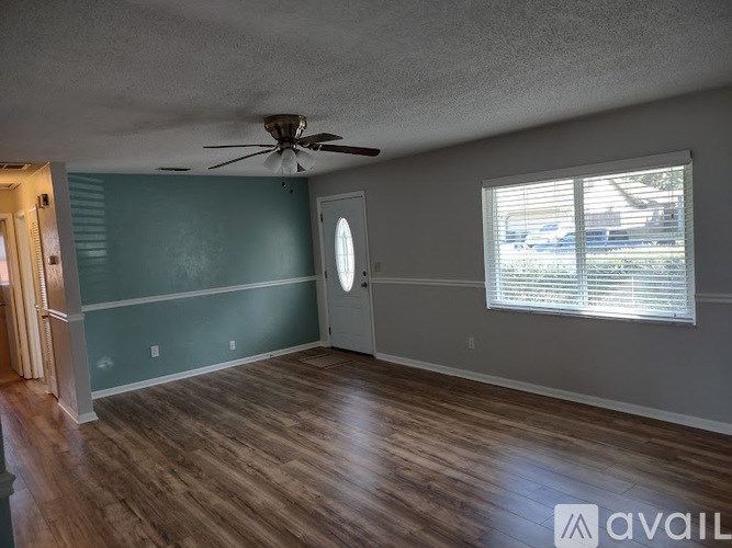 A room with a ceiling fan and a window with blinds.
