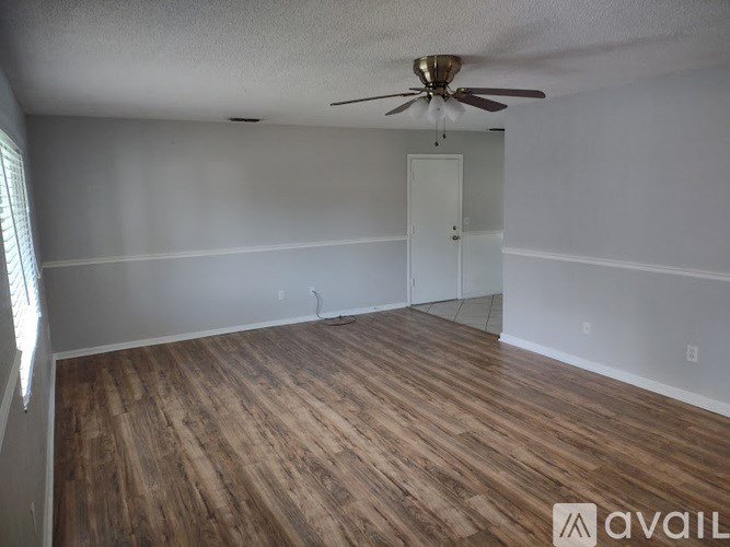 A room with wooden flooring and a ceiling fan.
