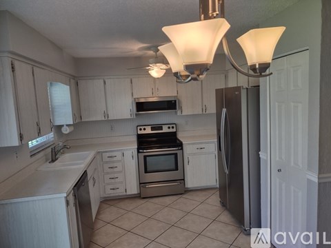 A kitchen with white cabinets and a black fridge.