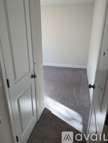 A hallway with a carpeted floor and white walls.