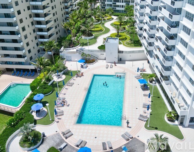 A large swimming pool surrounded by lounge chairs and umbrellas in a residential area.