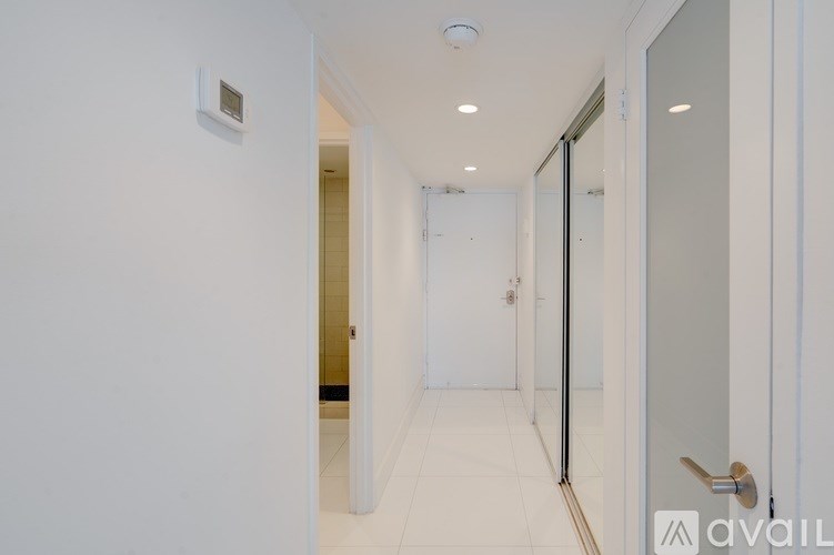A hallway with a door on the right and a wall-mounted thermostat on the left.