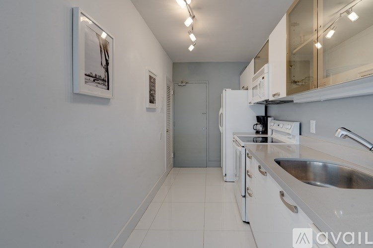 A kitchen with white cabinets and a stainless steel sink.