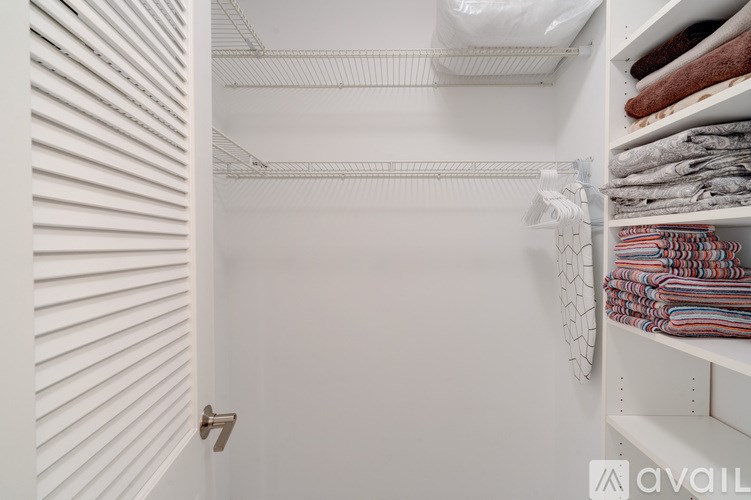 A white closet with clothes hanging on the rack.