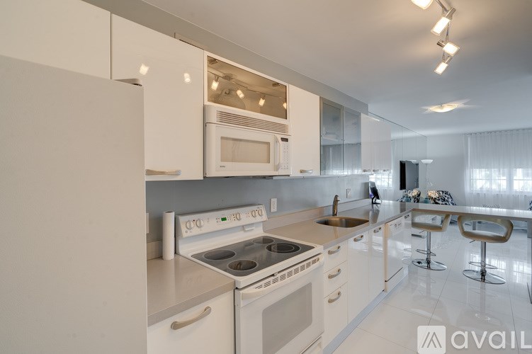 A modern kitchen with white appliances and a bar area.