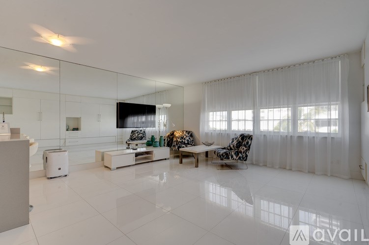 A modern living room with a white floor and a large mirror on the wall.