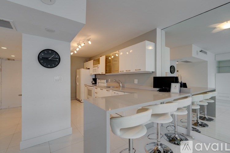 A modern kitchen with white furniture and a bar area.