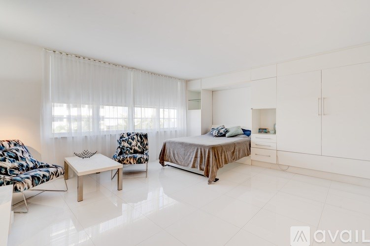 A bedroom with a bed, chair, and table.