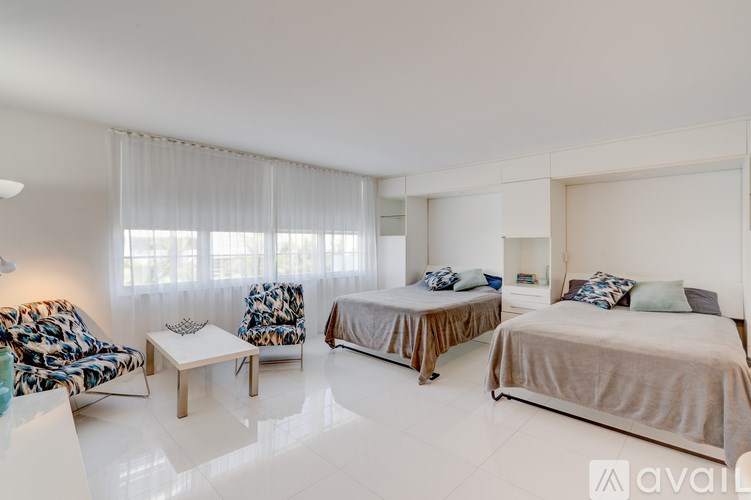 A bedroom with two beds and a chair with a patterned design.