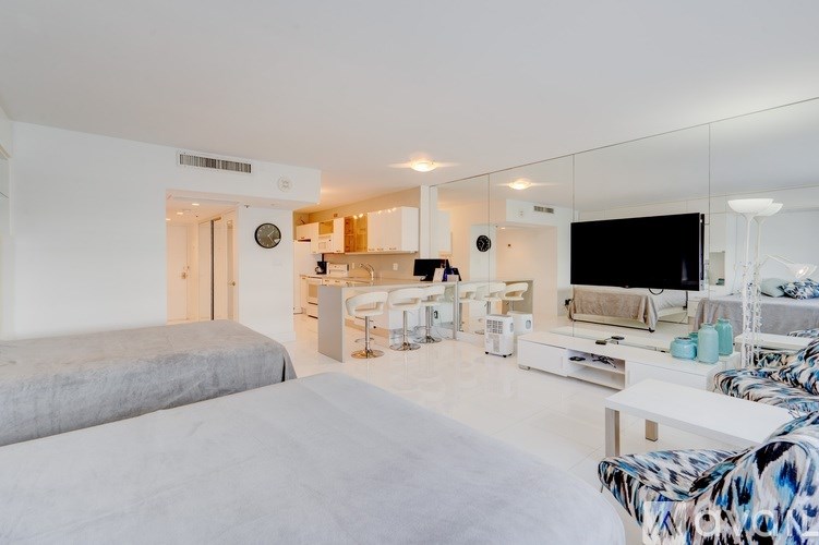 A modern living room with a grey bed and a white couch.