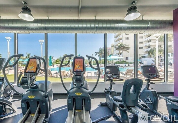 A gym with treadmills and a view of the pool and buildings outside.