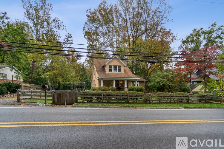 A house with a brown roof is surrounded by a fence and trees.
